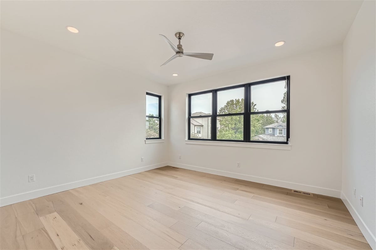 Second-floor bedroom with wood texture flooring, sliding windows, and a ceiling fan in a Sheffield Homes home in Superior, CO