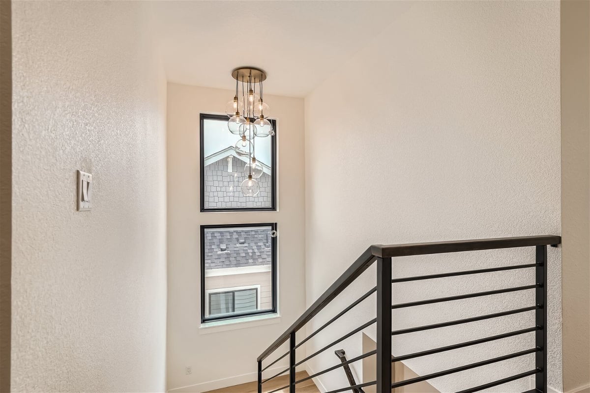 Second-floor landing with a fancy chandelier and metal railings in a Sheffield Homes home in Superior, CO