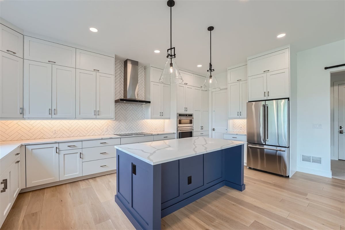 Side shot of a kitchen counter with a marble countertop and blue wooden base in a Sheffield Homes home, Superior, CO