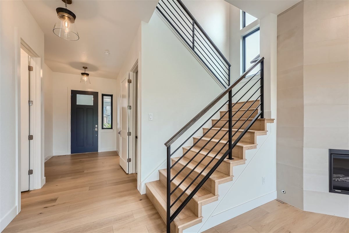 Stairway with wood-textured steps and metal railings landing in the living room of a Sheffield Homes home in Superior, CO