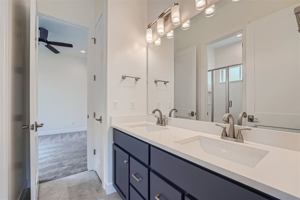 Bathroom with a vanity featuring dual faucets, a large mirror, and wooden cabinetry in a Sheffield Homes home in Superior, CO