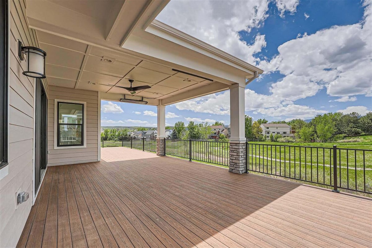 Deck with a central wooden hood, stone accent pillar columns, and a metal fence in a Sheffield Homes home in Superior, CO