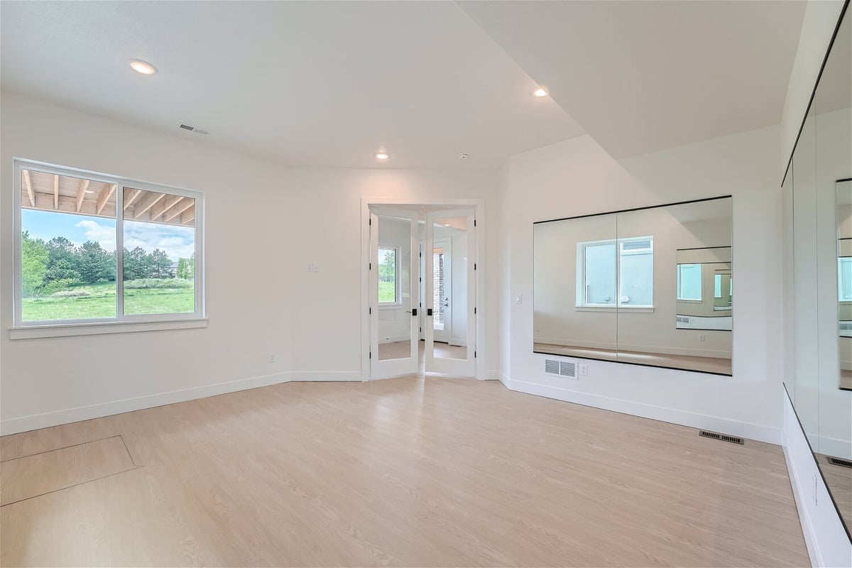Lower-level exercise room with two large wall mirrors, an access door, and a window in a Sheffield Homes home in Superior, CO
