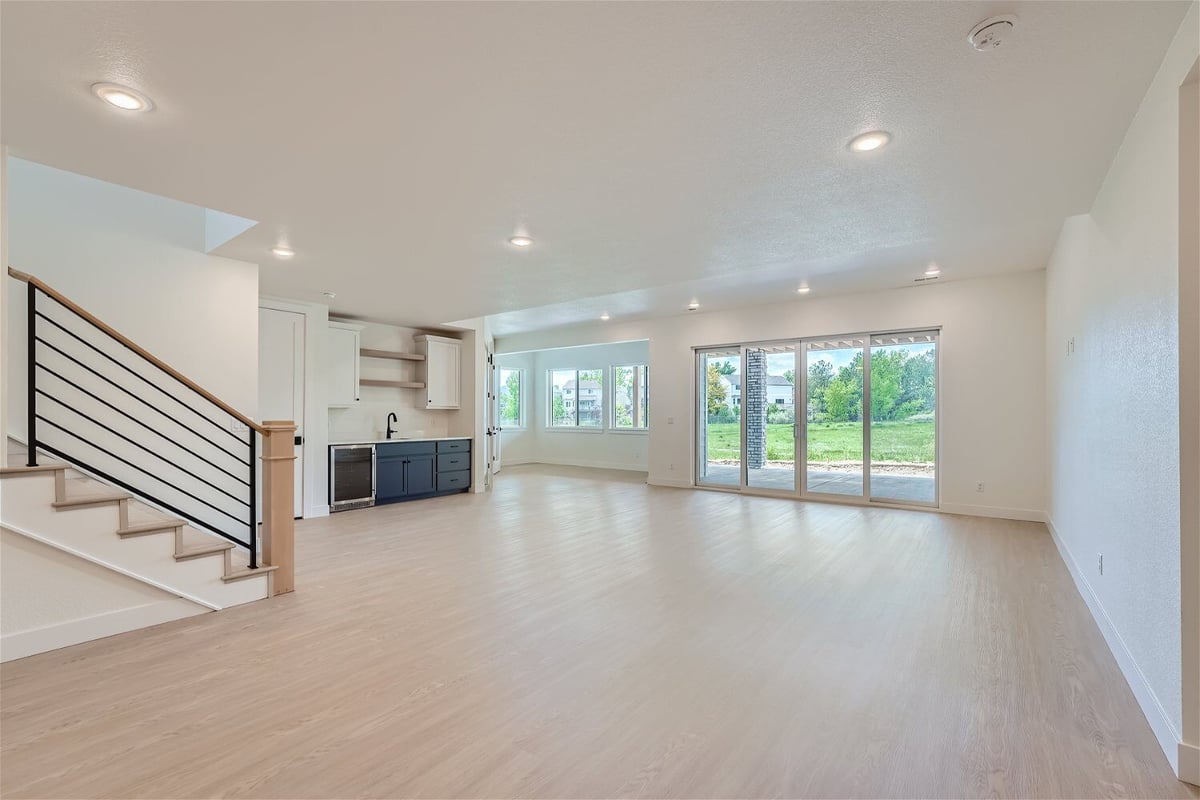 Lower-level family room with a corner wet bar, large sliding doors, and a stairway in a Sheffield Homes home in Superior, CO