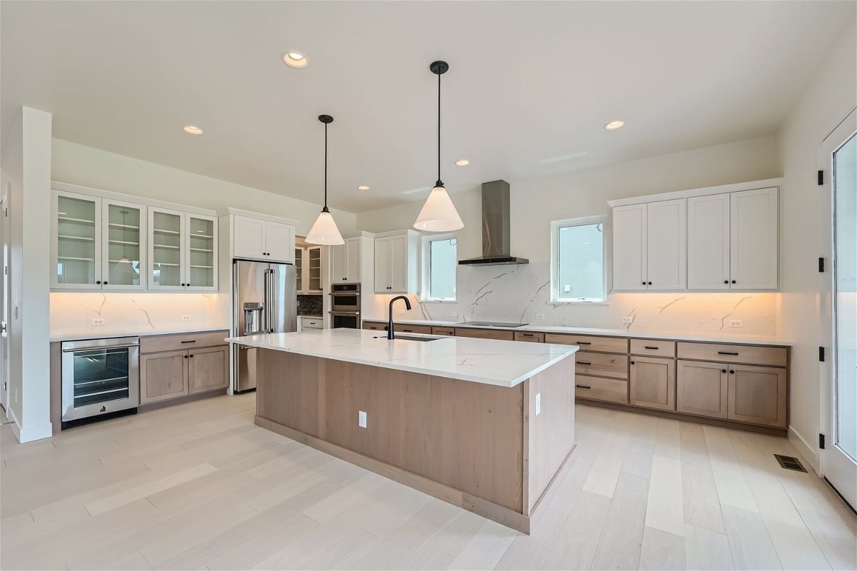 Open kitchen with a central island, pendant light fixtures, and sleek cabinetry in a Sheffield Homes home in Superior, CO