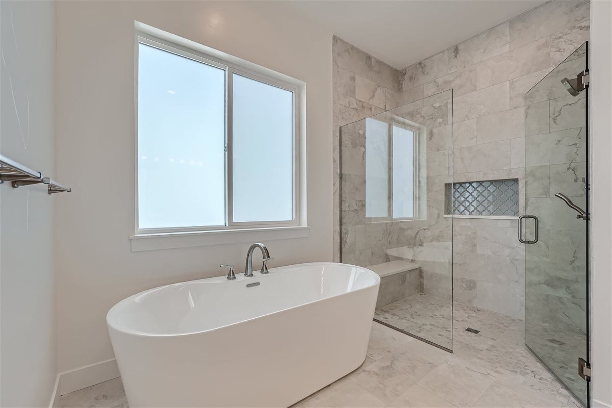 Primary bathroom with a freestanding tub and a shower room with a glass door in a Sheffield Homes home in Superior, CO