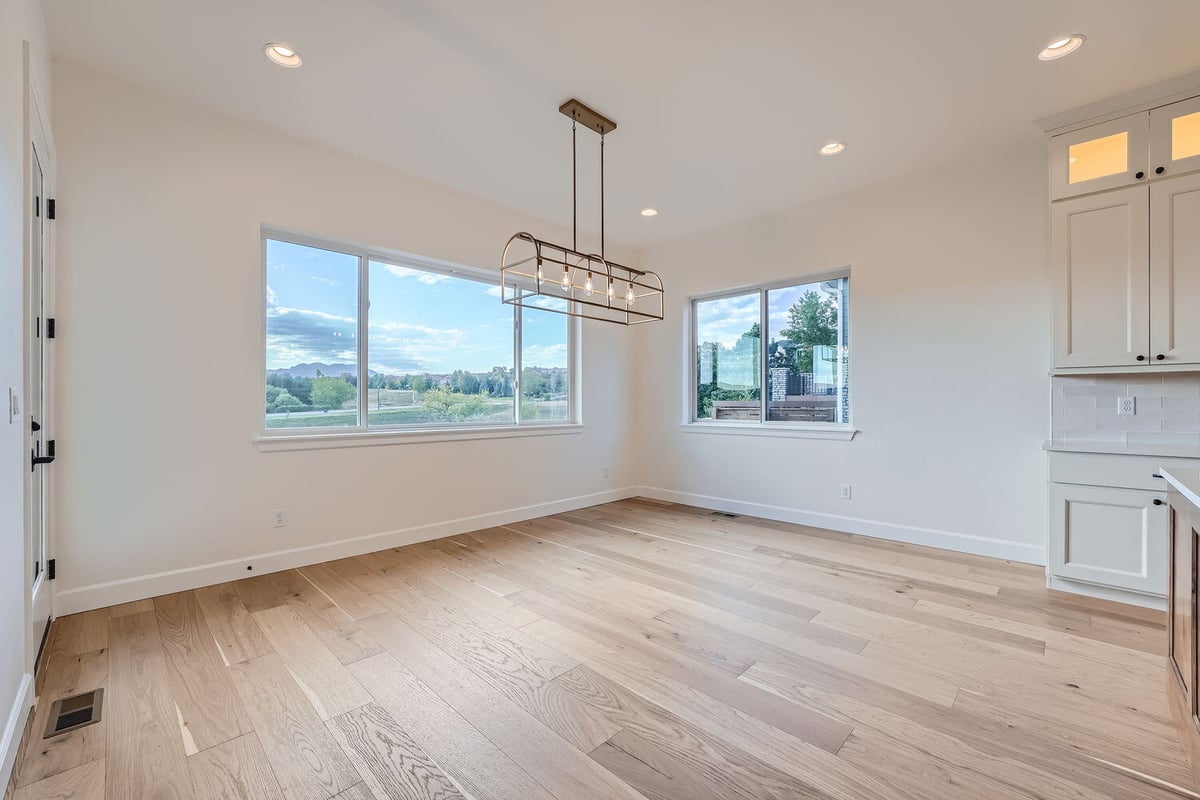 Alternate view of the dining room in a Sheffield Homes custom home in Denver, CO, with large windows and hardwood floors