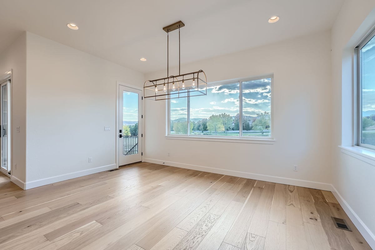 Bright dining room in a Sheffield Homes custom home in Denver, CO, with large windows and modern light fixtures