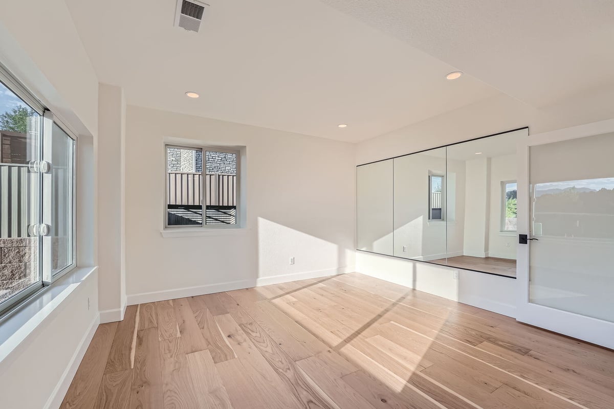 Light-filled exercise room with mirrored wall in a custom home by Sheffield Homes, Denver, CO