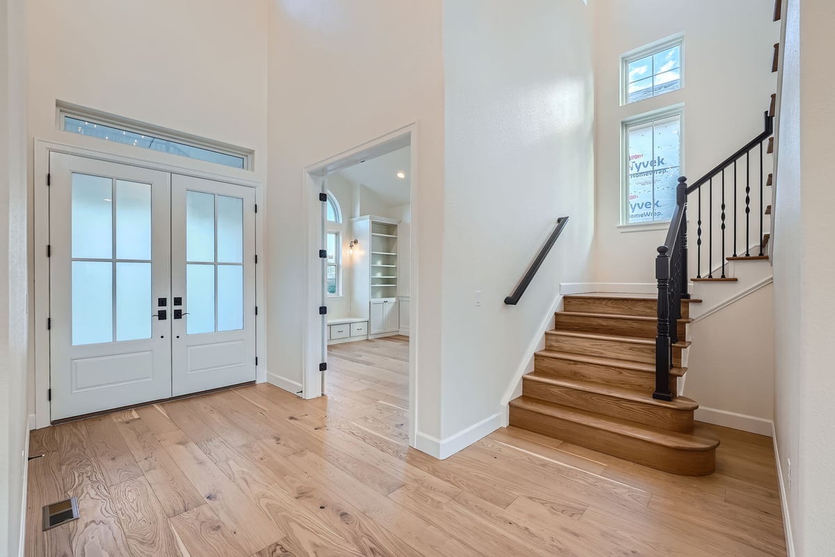 Spacious foyer of a custom-built home by Sheffield Homes in Denver, CO, featuring natural wood flooring and bright entry doors