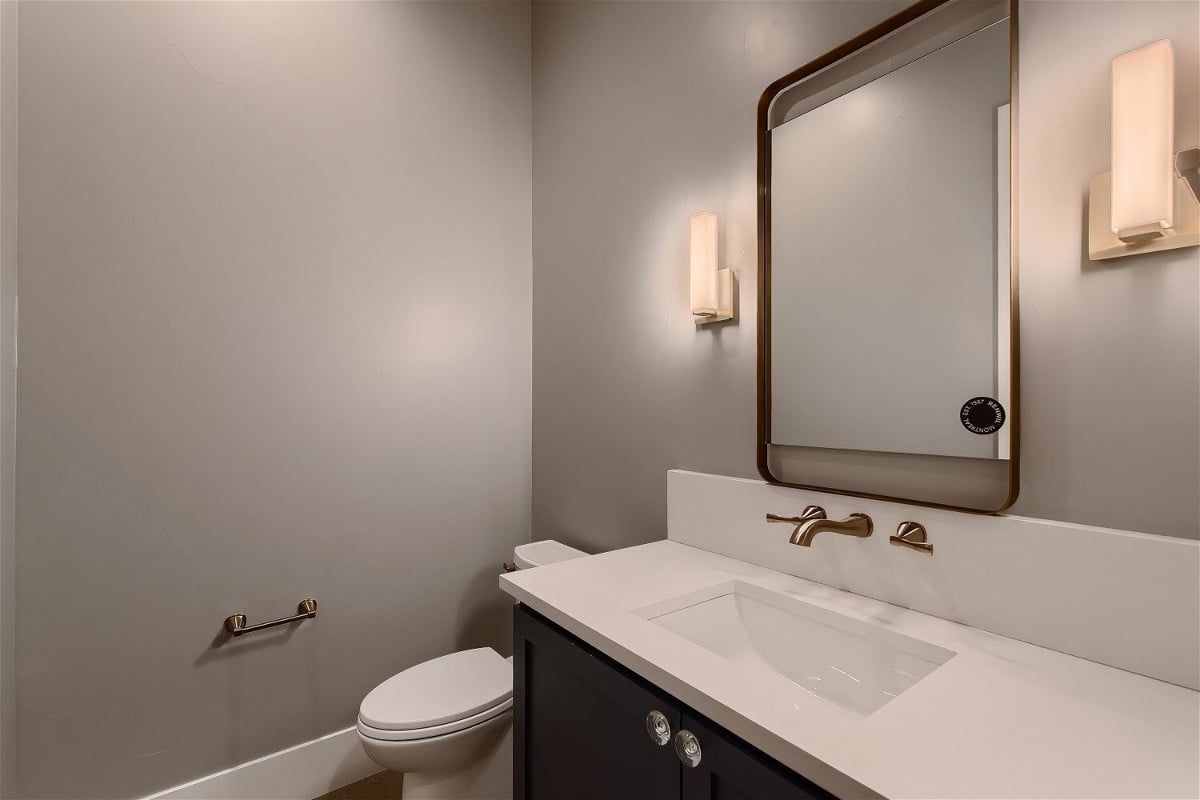 Minimalist powder room design in a Sheffield Homes custom home in Denver, CO, featuring a modern vanity and lighting