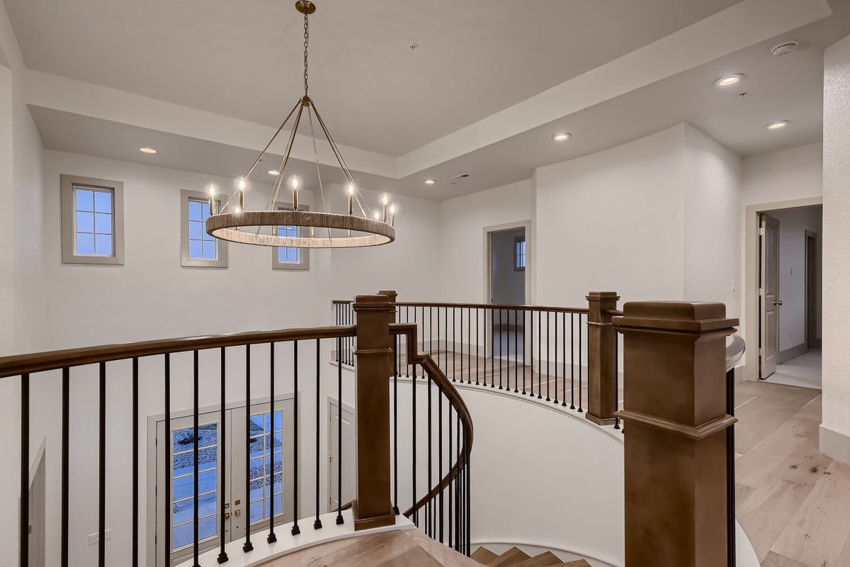 An elegant chandelier with lit-up candles, viewed from the second-floor staircase, in a Sheffield Homes home, Westminster, CO