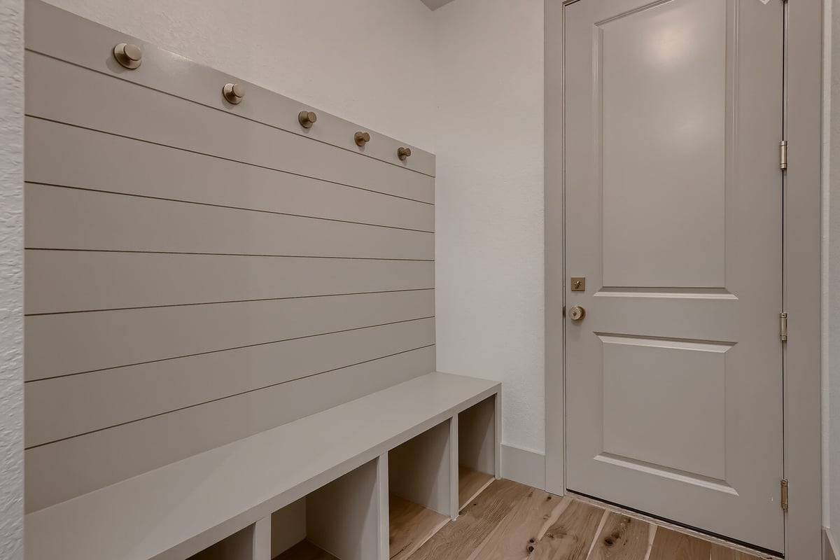 Compact mudroom with vinyl flooring, white cabinetry, and cloth hanging hooks in a Sheffield Homes home in Westminster, CO