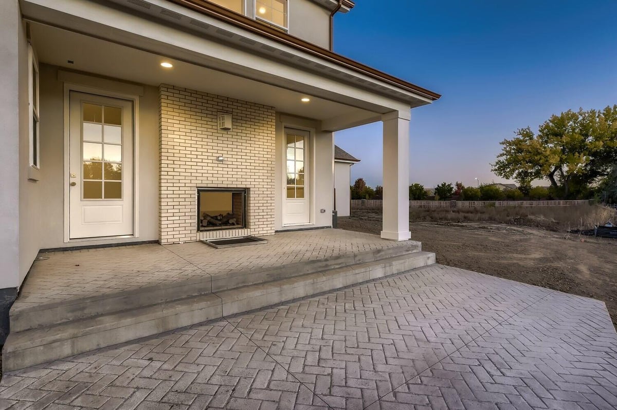 Custom patio with diagonal brick flooring, a wall-mounted fireplace, and access doors, by Sheffield Homes in Westminster, CO