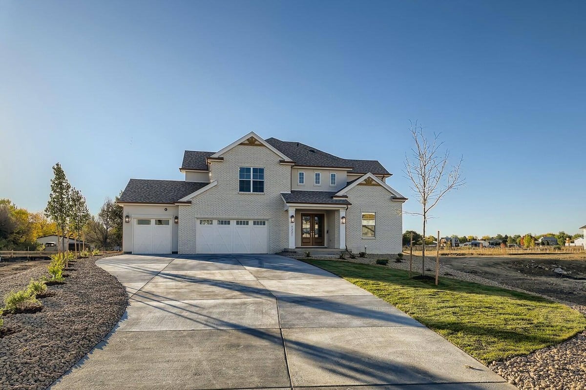 Daylight shot of the exterior front of a custom home with an outdoor lawn and driveway, by Sheffield Homes in Westminster, CO