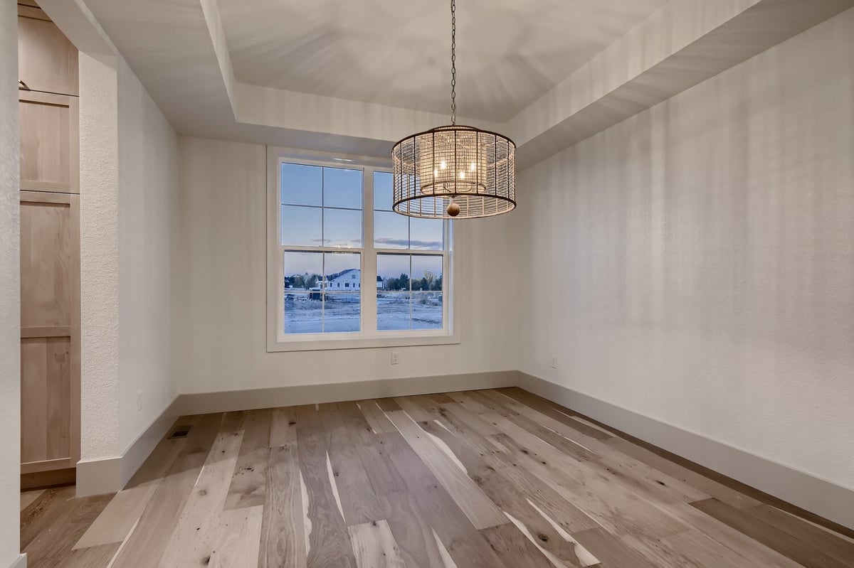 Dining room with vinyl flooring, a bright pendant chandelier, and a window in a Sheffield Homes home in Westminster, CO