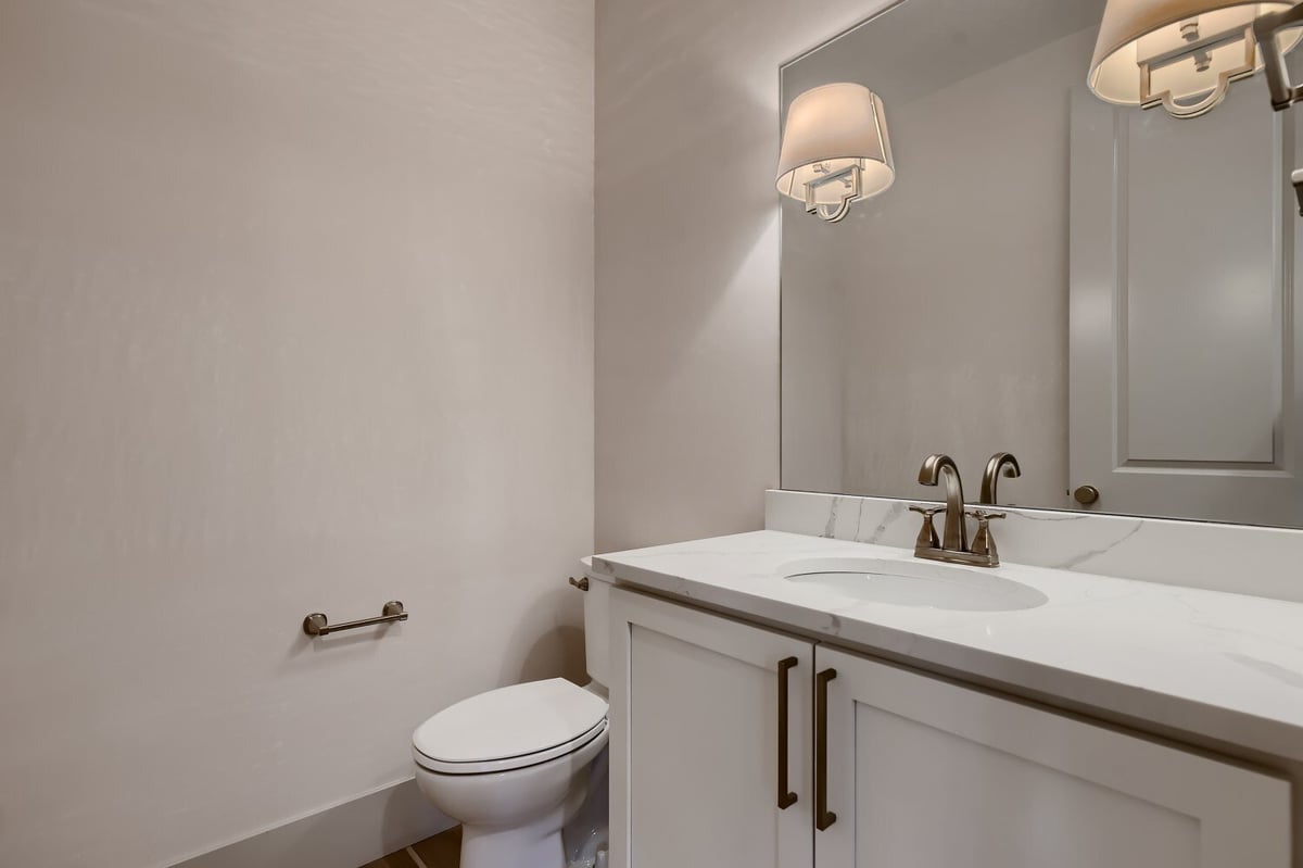 Elegant powder room with a vanity, stylish lighting, and a toilet in a custom home by Sheffield Homes in Westminster, CO