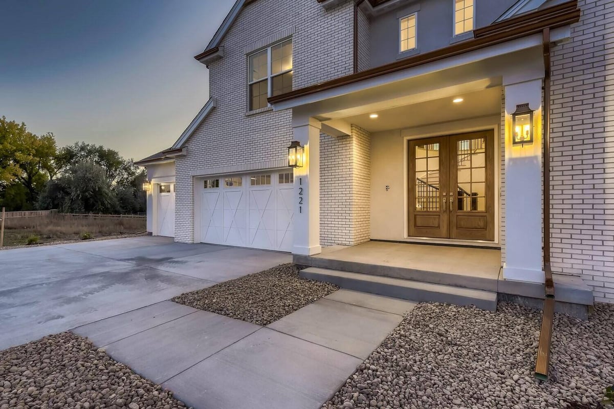 Exterior front entry of a home with elegant lights and a pathway surrounded by pebbles, by Sheffield Homes, Westminster, CO