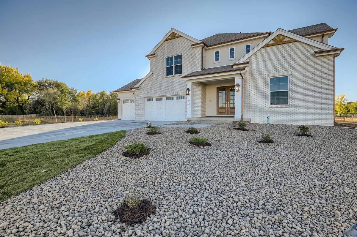 Exterior front of a home featuring custom wall design, with pebbles in the outdoor lawn, by Sheffield Homes, Westminster, CO