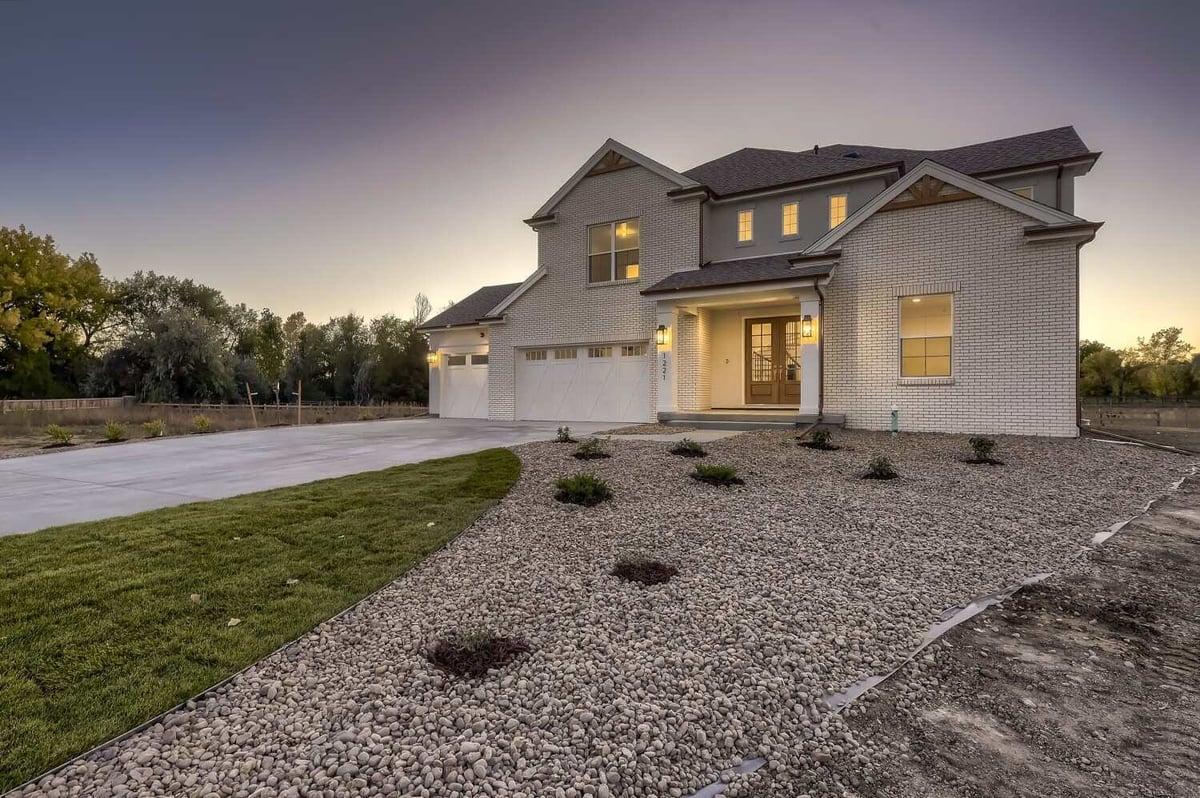 Exterior front view of a custom home with elegant lights, and a pebble and grass lawn, by Sheffield Homes in Westminster, CO