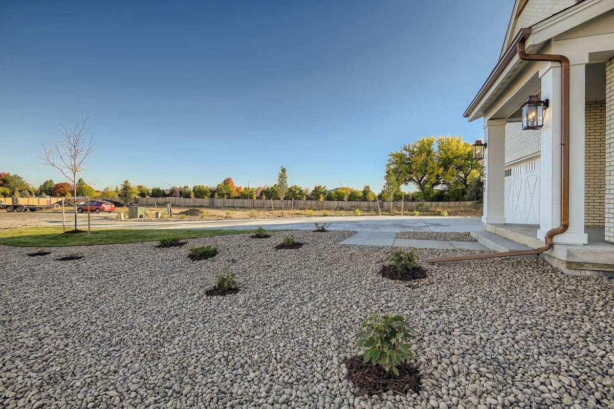 Exterior side view of a home with an outdoor lawn covered in mini plants and pebbles, by Sheffield Homes in Westminster, CO