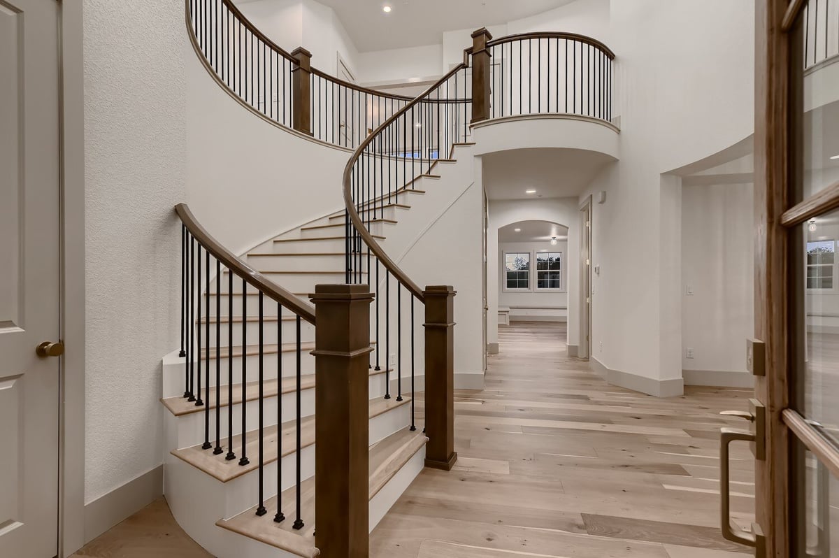 Foyer with a curved staircase featuring wooden railings and a metal fence in a Sheffield Homes custom home in Westminster, CO