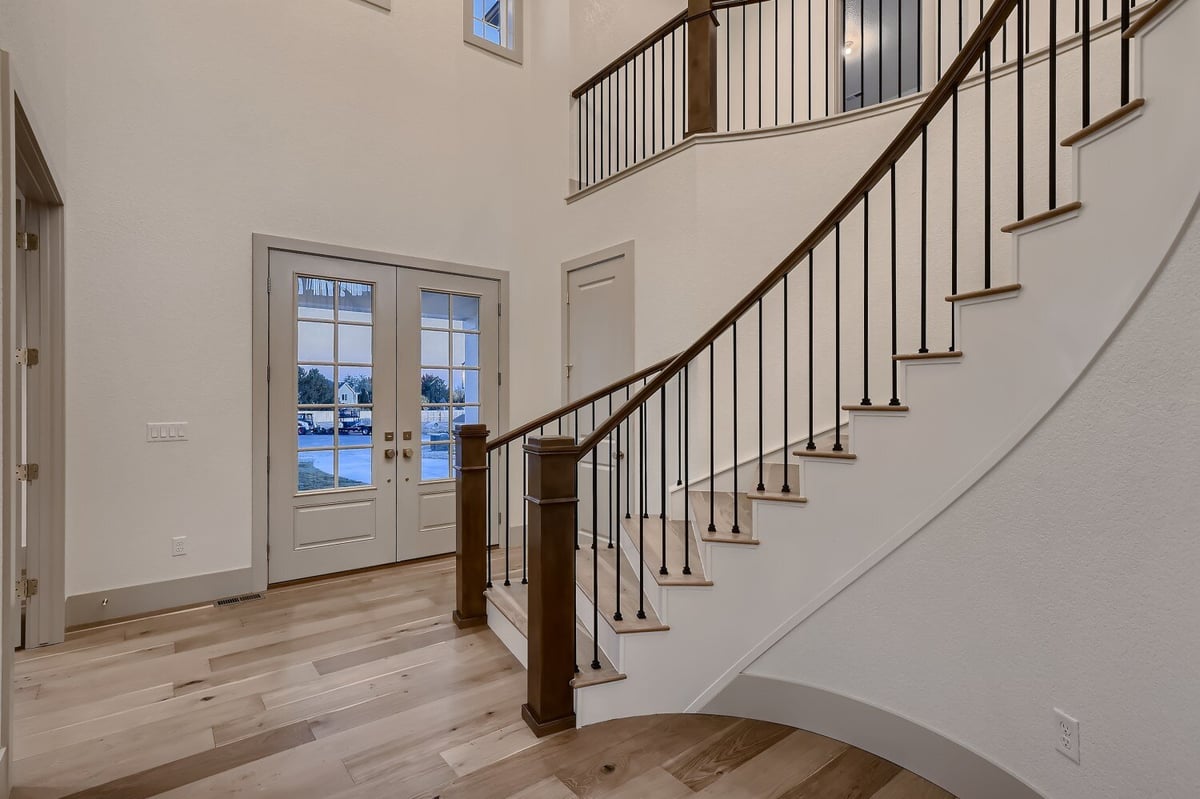 Foyer with wooden texture flooring and a curved staircase in a Sheffield Homes custom home in Westminster, CO