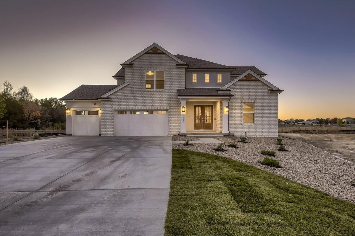 Low-light exterior front view of a custom home with a garage, driveway, and front yard, by Sheffield Homes in Westminster, CO