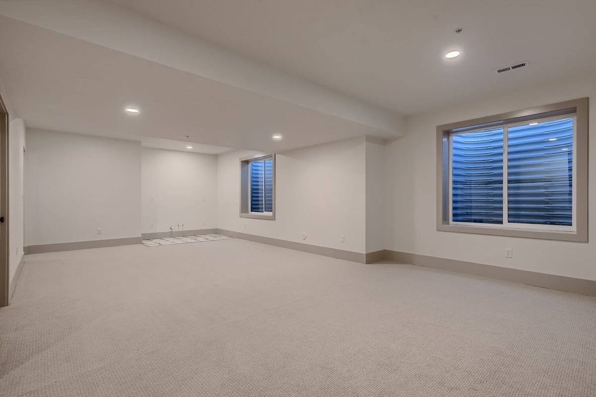 Lower-level family room with carpet flooring and a couple of large windows in a Sheffield Homes home in Westminster, CO