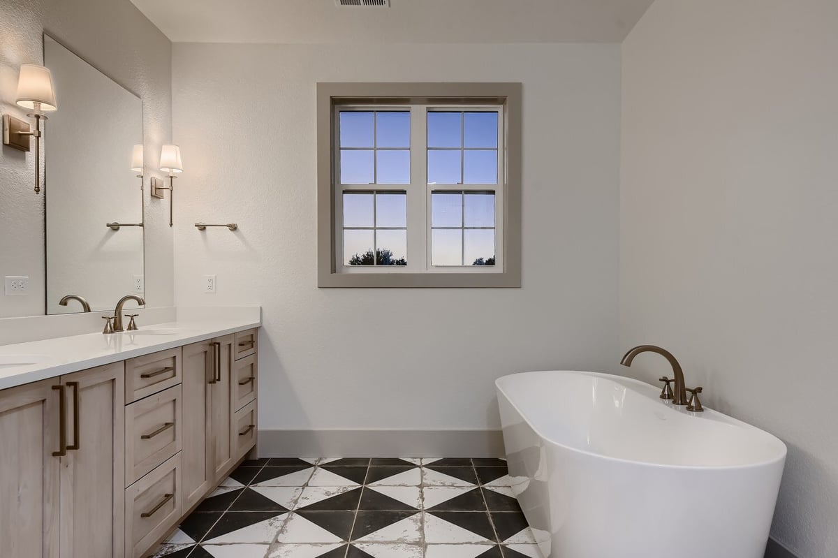 Primary bathroom with a checked floor design, a freestanding tub, and dual vanities, by Sheffield Homes in Westminster, CO