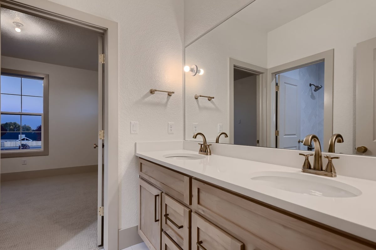 Second-floor Jack and Jill bedroom with dual vanities and light fixtures in a Sheffield Homes home in Westminster, CO