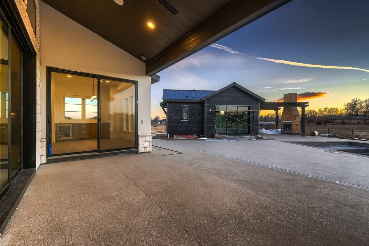 Custom patio with a wooden hood, elegant lighting fixtures, and access doors, by Sheffield Homes in Westminster, CO