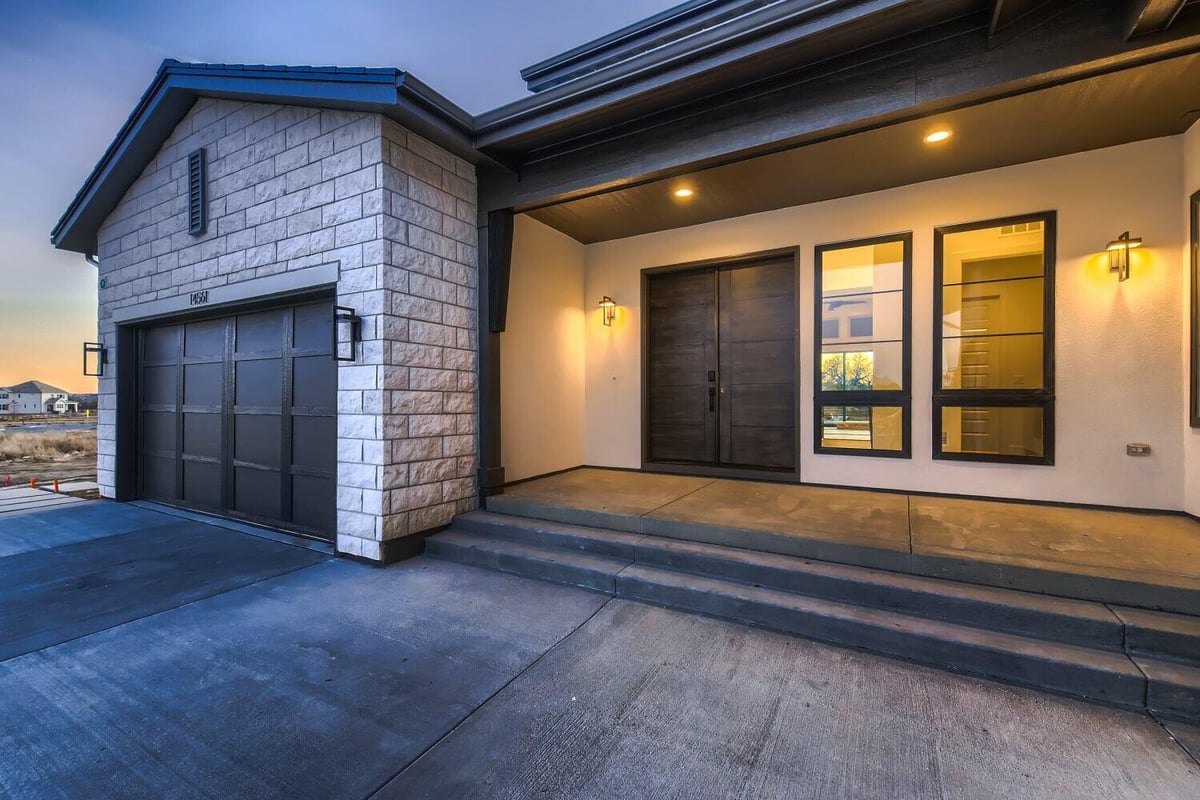 Exterior front entrance of a home with a garage on the left and elegant light fixtures, by Sheffield Homes in Westminster, CO