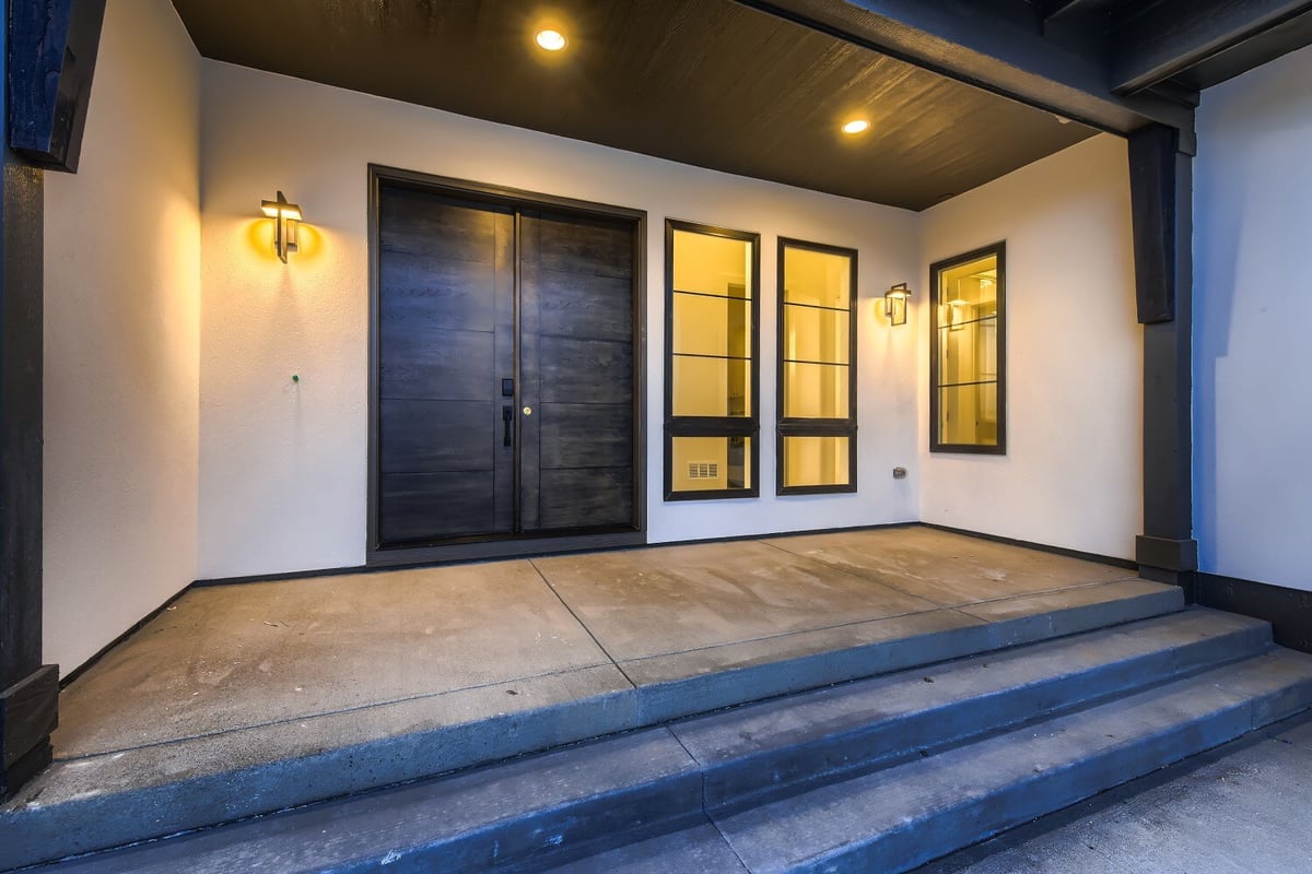 Exterior front entrance of a home with a wooden main door and elegant light fixtures, by Sheffield Homes in Westminster, CO