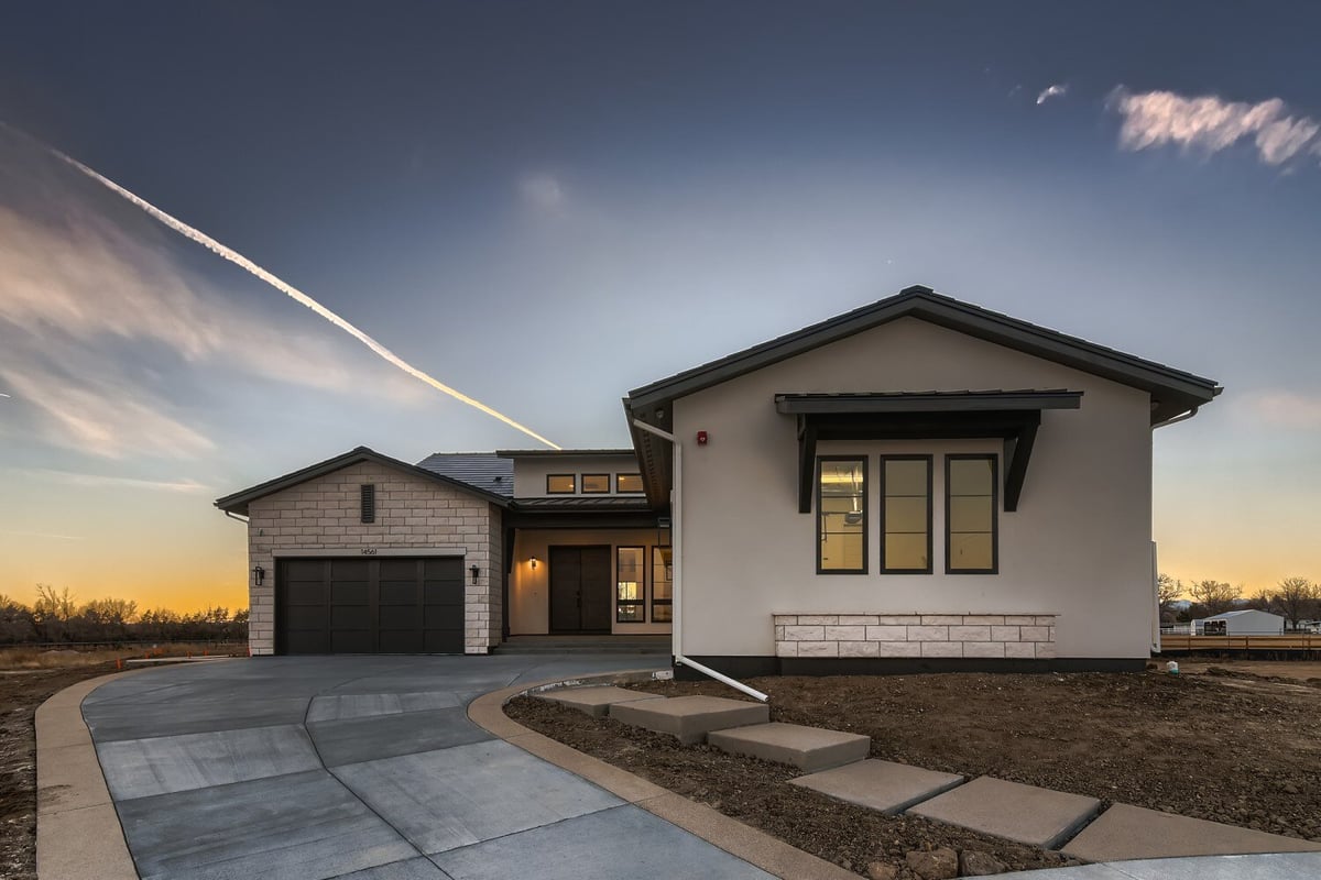 Low-angle exterior front view of a custom home with a paved driveway and a front yard, by Sheffield Homes in Westminster, CO