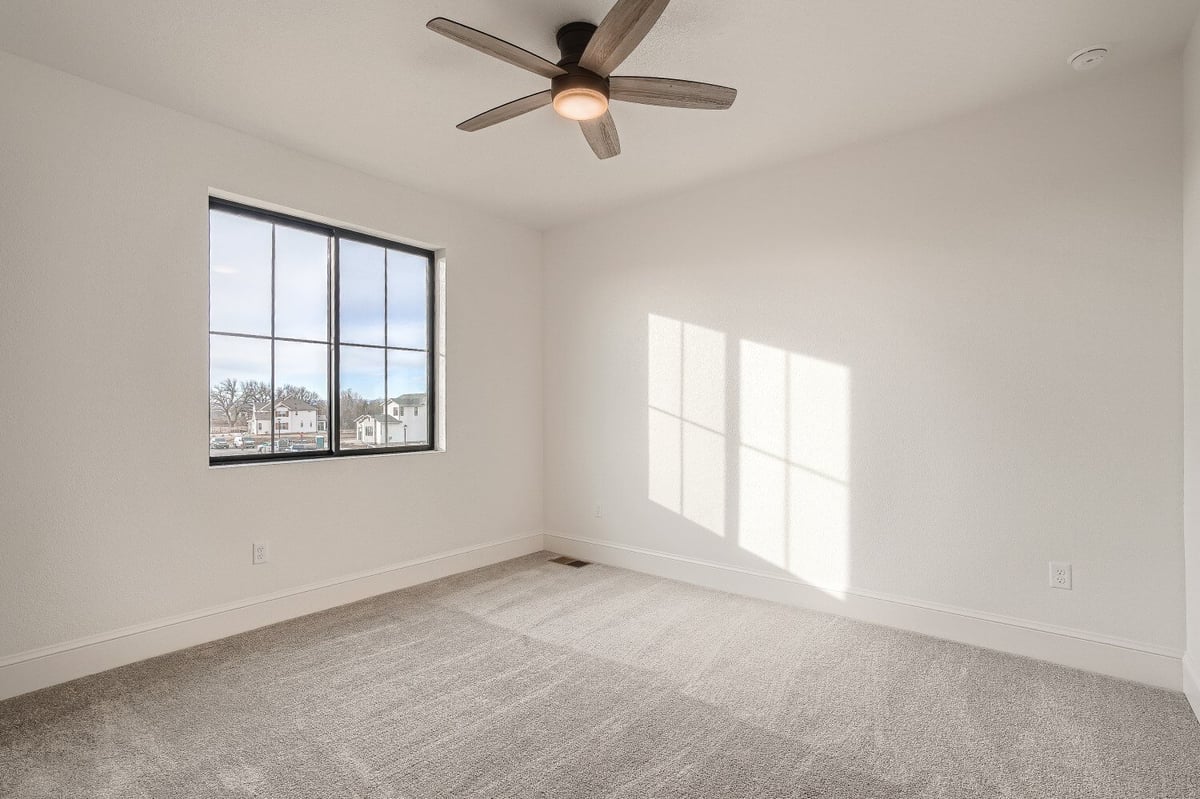 Bedroom with carpet flooring, a ceiling fan, and a sliding window in a custom home by Sheffield Homes in Westminster, CO