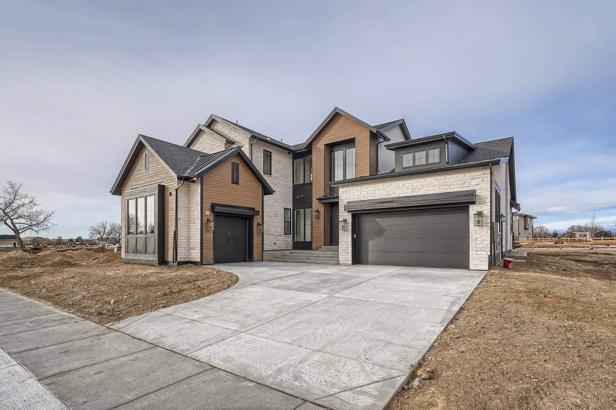 Daylight exterior front view of a custom home with a garage and a paved driveway, by Sheffield Homes in Westminster, CO