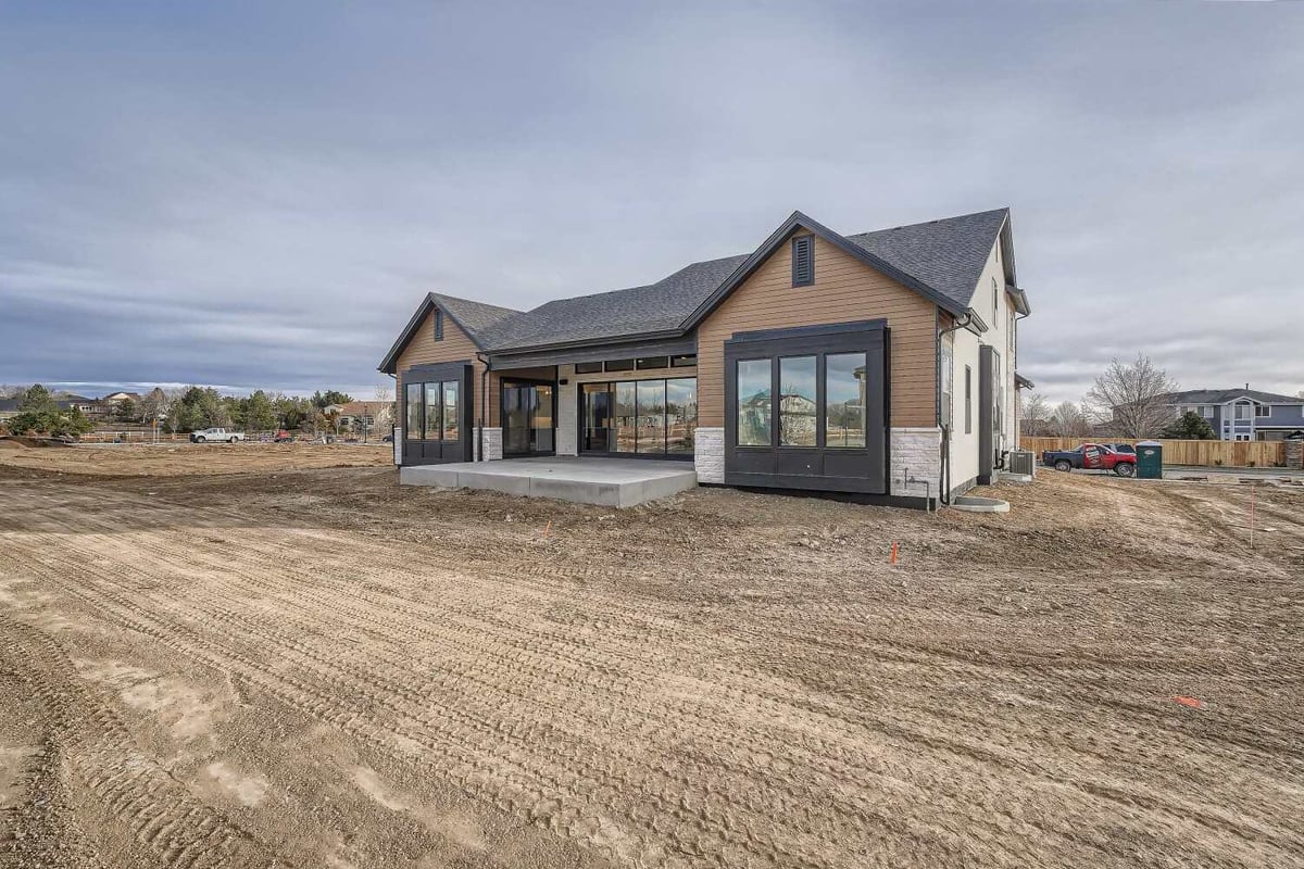 Daylight long shot of the rear exterior of a custom home with a large backyard, built by Sheffield Homes in Westminster, CO