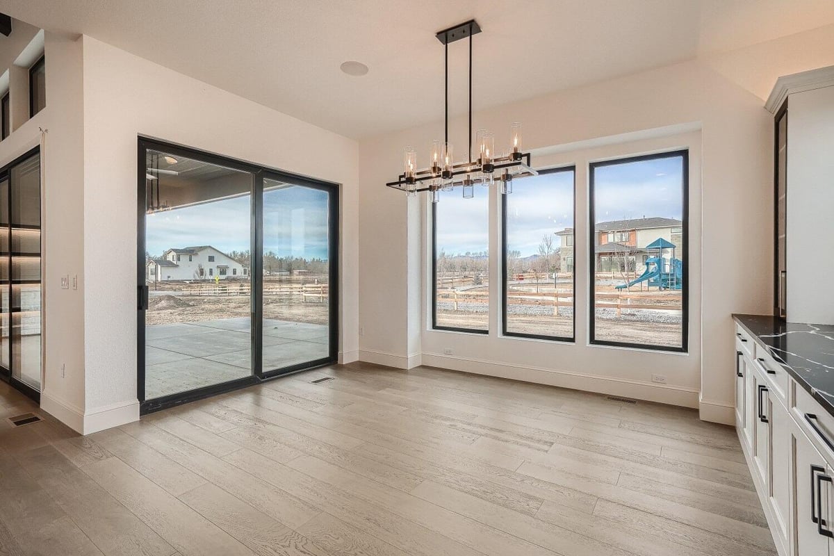 Dining room with a candle-lit pendant chandelier, sliding door, windows, and a wetbar, by Sheffield Homes in Westminster, CO-1