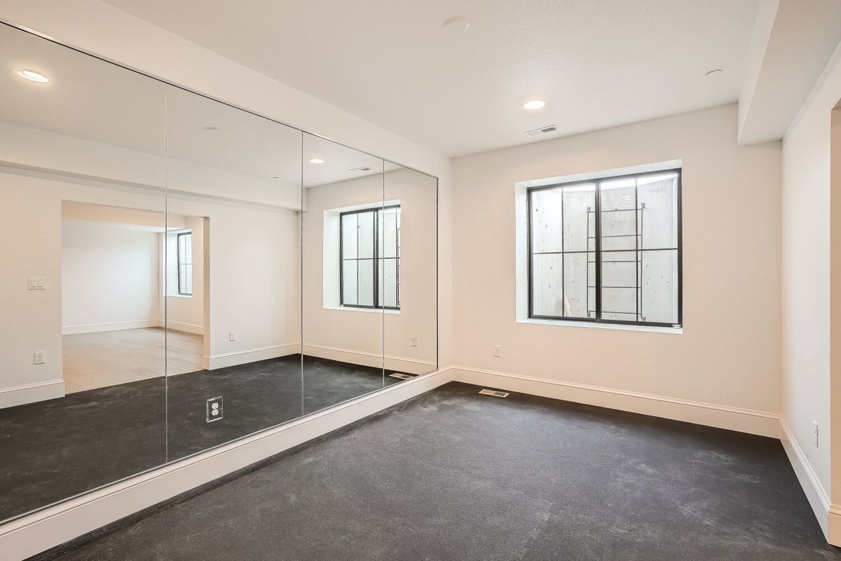 Exercise room with large wall mirrors, dark carpeting, and windows for ventilation in a Sheffield Homes home, Westminster, CO