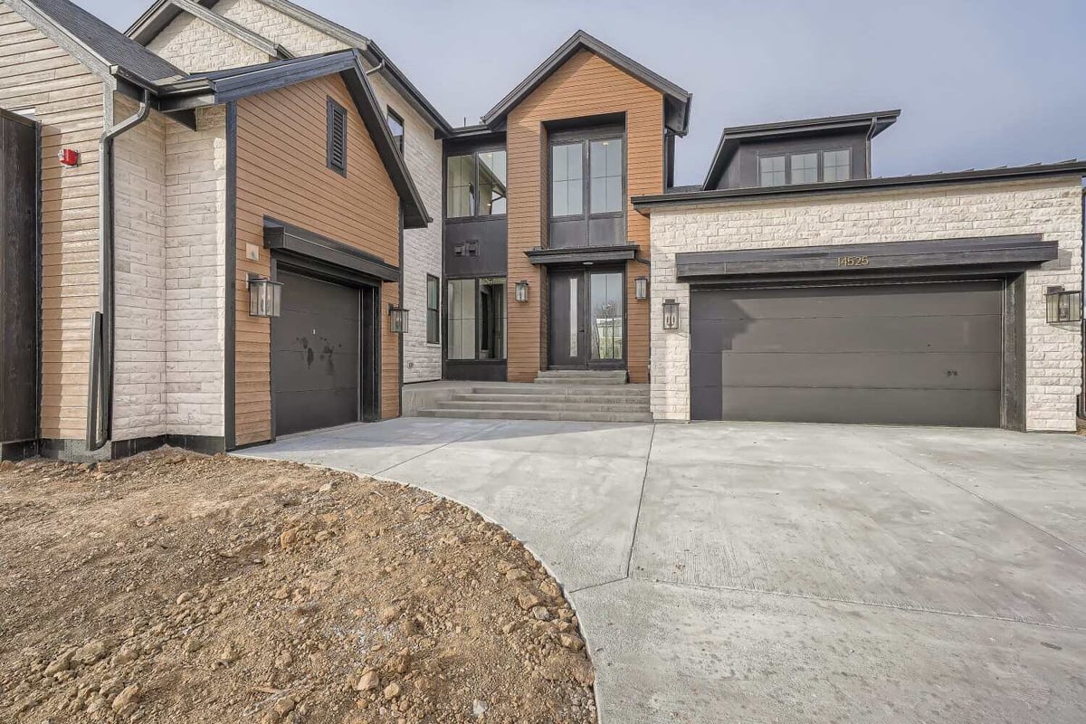 Exterior front entrance of a custom home featuring a main door and two garage entrances, by Sheffield Homes, Westminster, CO