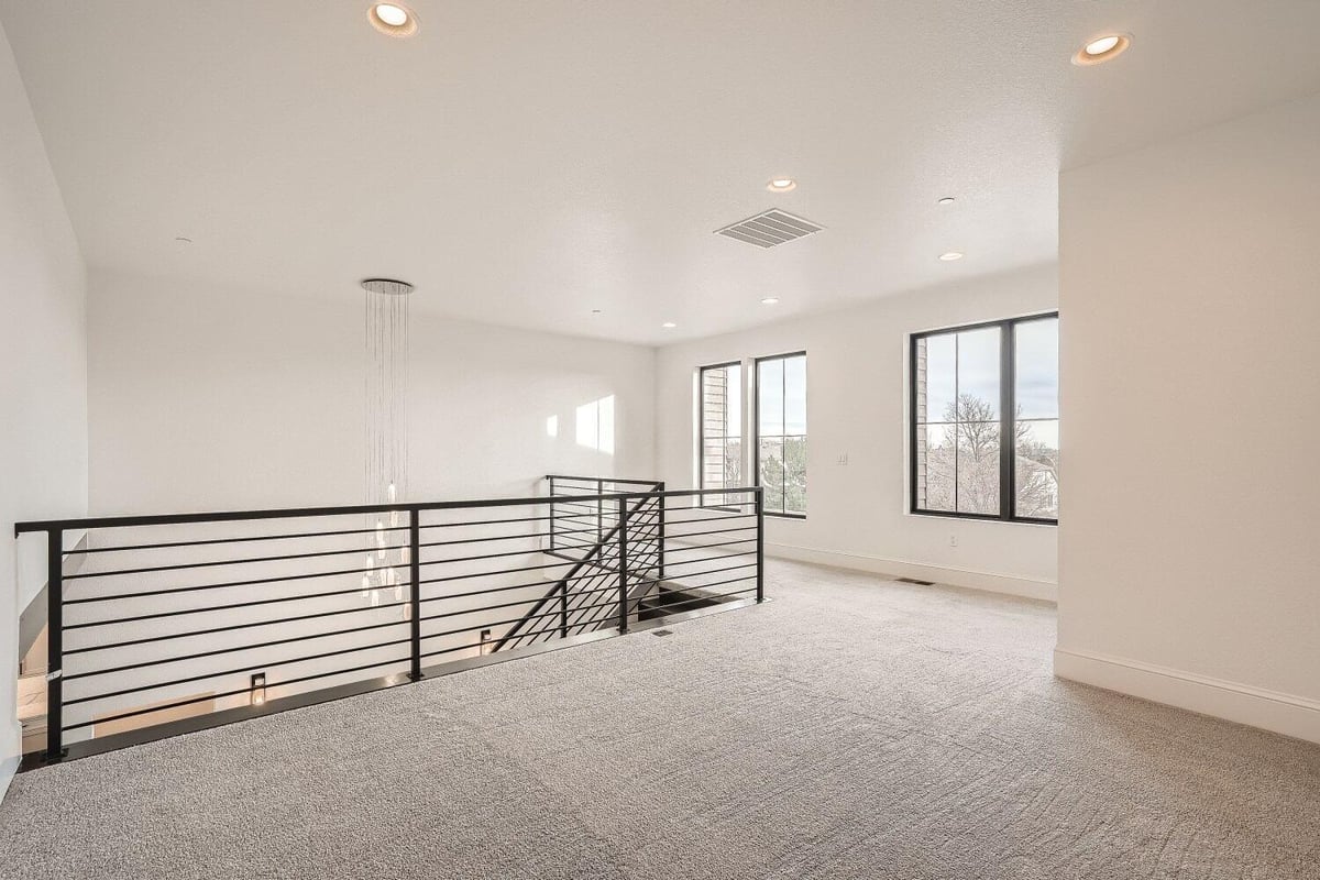 Loft with carpet flooring and railings with natural light coming through windows, by Sheffield Homes in Westminster, CO