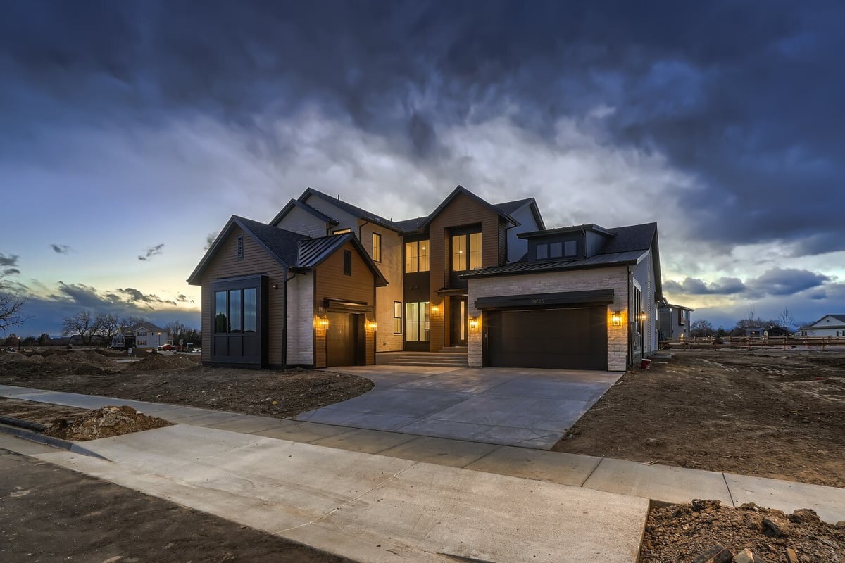 Low-light exterior front view of a large custom home with a paved walkway, by Sheffield Homes in Westminster, CO