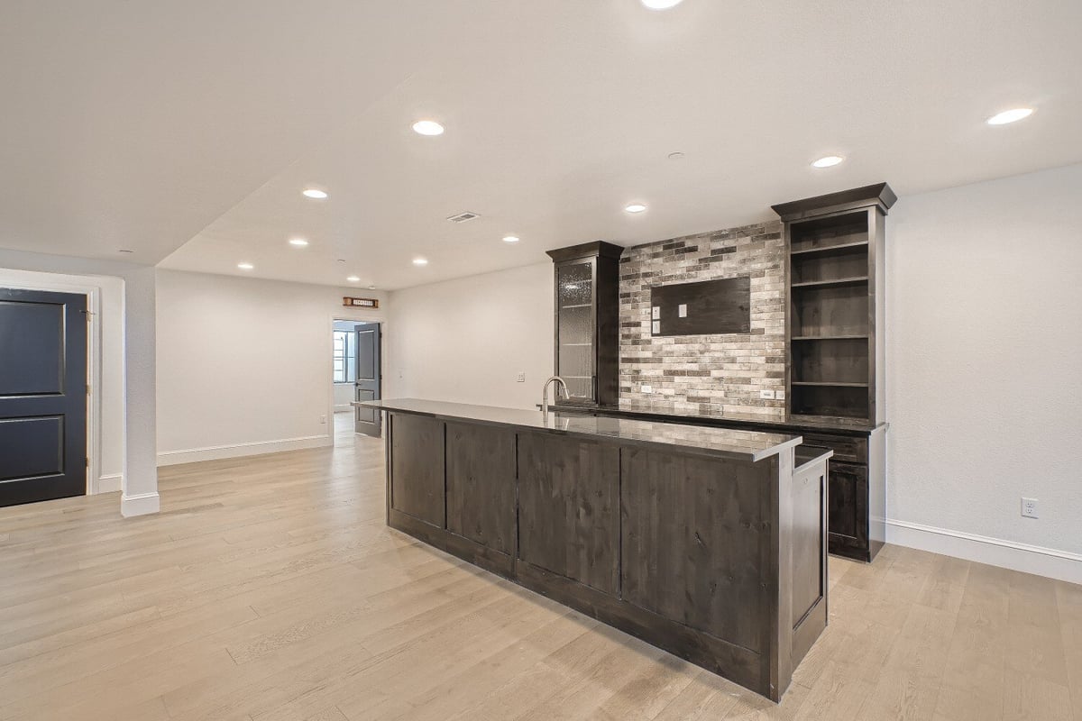 Lower level wetbar with grey cabinetry in the living room with vinyl flooring in a Sheffield Homes home in Westminster, CO