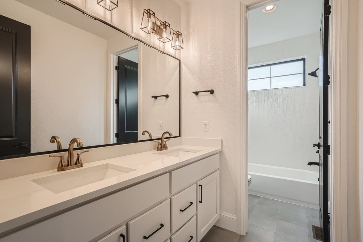 Modern bathroom with elegant lighting, dual vanity, and golden faucet fixtures in a Sheffield Homes home in Westminster, CO