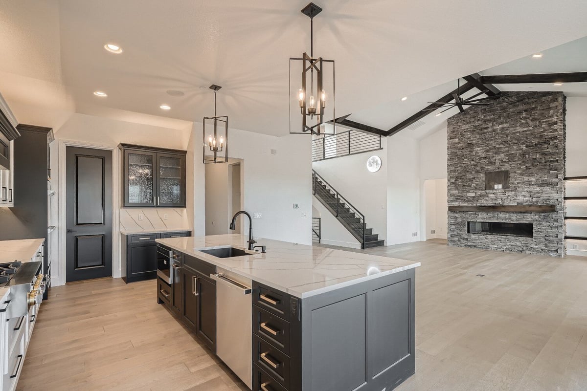 Modern island with a marble countertop, and wood and steel drawers, in an open kitchen by Sheffield Homes in Westminster, CO