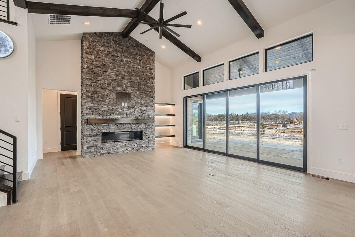 Modern living room with a mounted fireplace and four sliding access doors in a home by Sheffield Homes in Westminster, CO