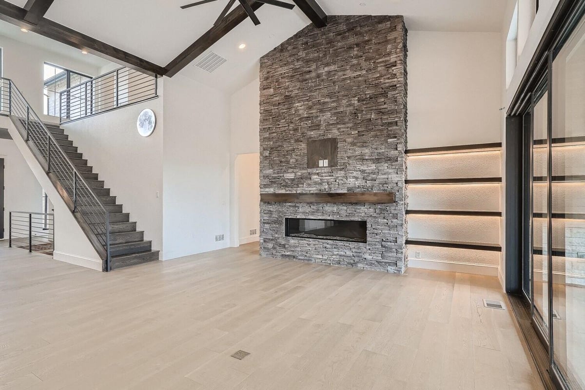 Modern living room with a staircase and a feature wall with a mounted fireplace in a Sheffield Homes home, Westminster, CO