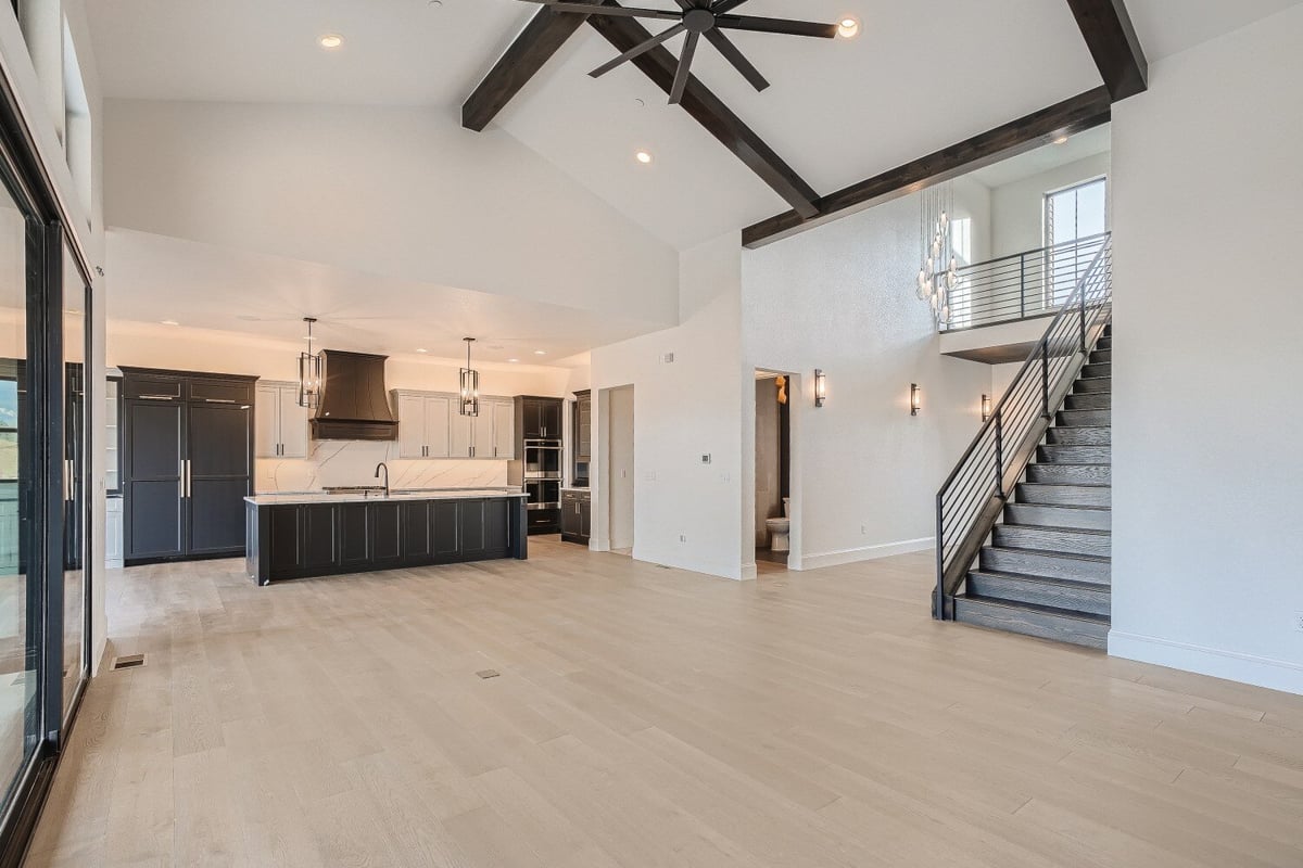 Modern living room with an open kitchen, staircase with metal railings, and a ceiling fan by Sheffield Homes, Westminster, CO