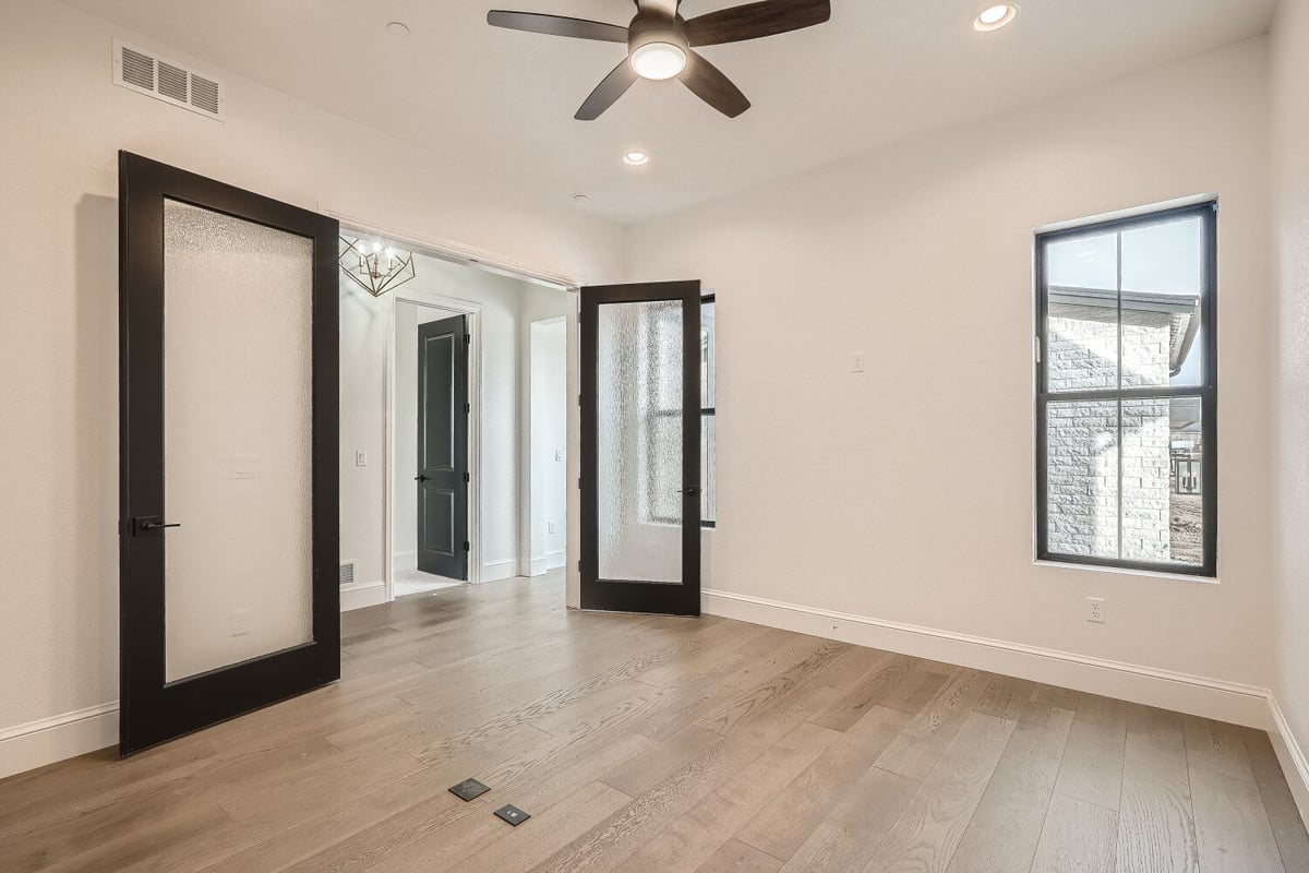 Office with vinyl flooring, a ceiling fan, multiple windows, and doors in a custom home by Sheffield Homes in Westminster, CO